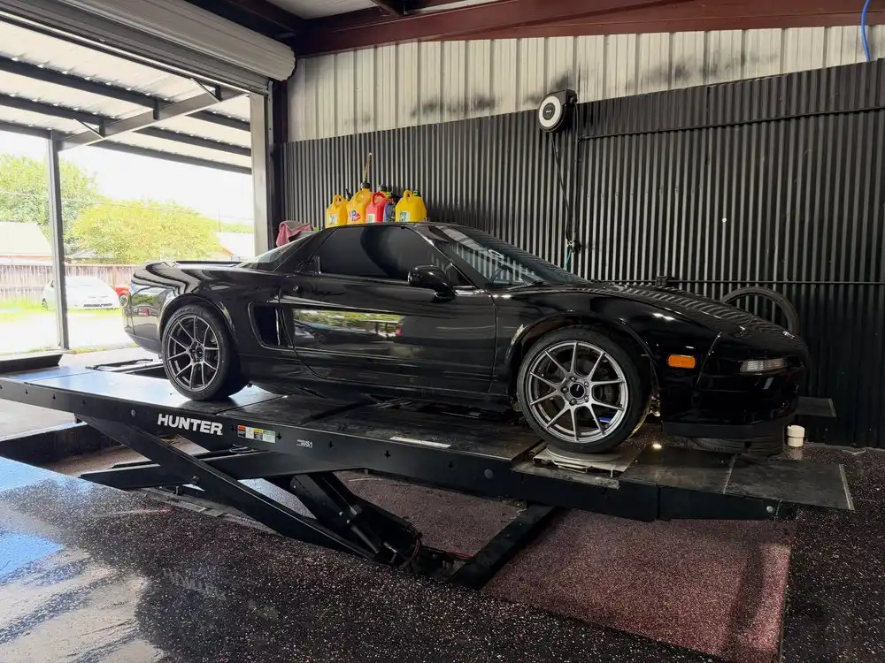 Black Acura NSX on a Hunter alignment rack inside the shop bay