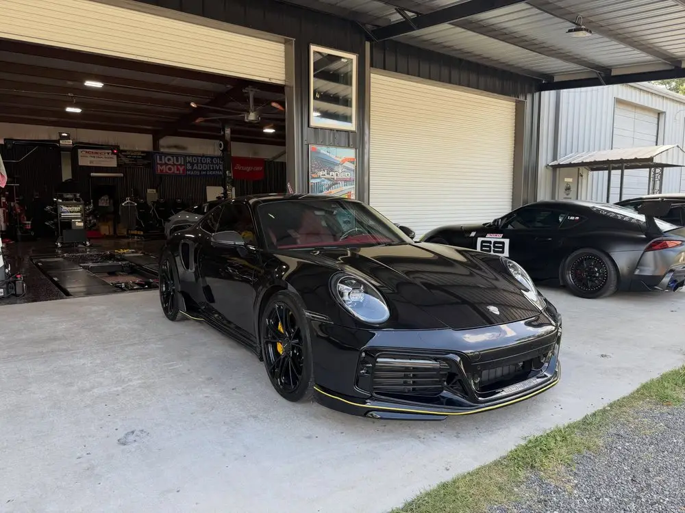 Black Porsche 911 Turbo parked at the open bay doors of the shop